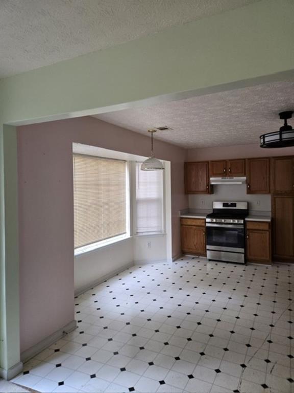 kitchen featuring stainless steel stove, decorative light fixtures, and a textured ceiling