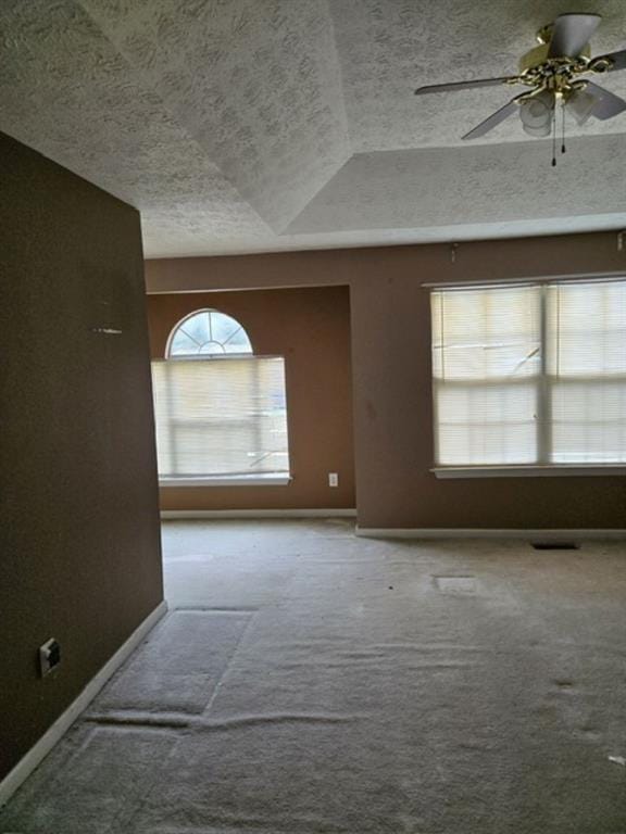 empty room featuring ceiling fan, a textured ceiling, lofted ceiling, and carpet