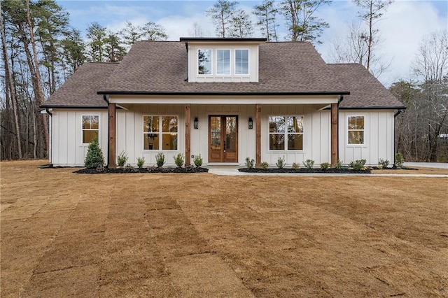 modern inspired farmhouse with board and batten siding, a front yard, french doors, and roof with shingles