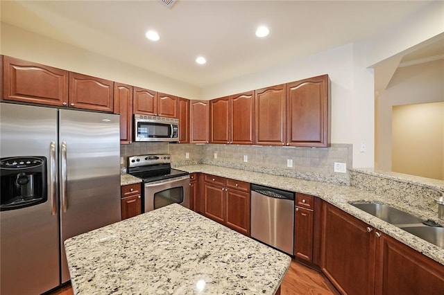 223 Glens Loop, Woodstock, GA 30188 - kitchen featuring stainless steel appliances, light wood finished floors, light stone counters, decorative backsplash, and a sink