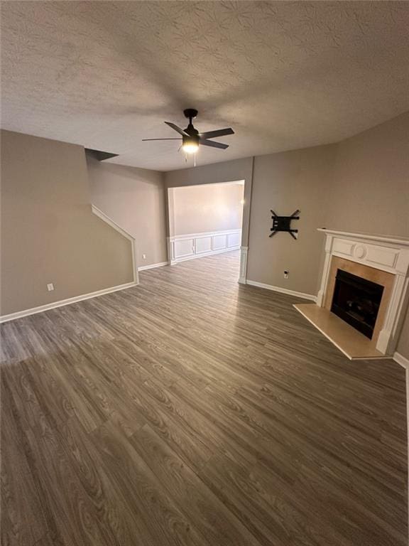 unfurnished living room with dark hardwood / wood-style floors, ceiling fan, and a textured ceiling