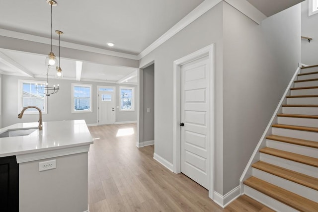 kitchen with an inviting chandelier, light hardwood / wood-style floors, ornamental molding, pendant lighting, and sink