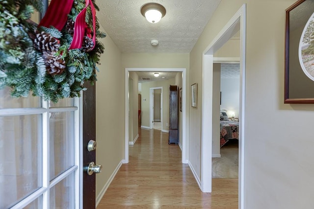 hallway featuring a textured ceiling and light hardwood / wood-style floors