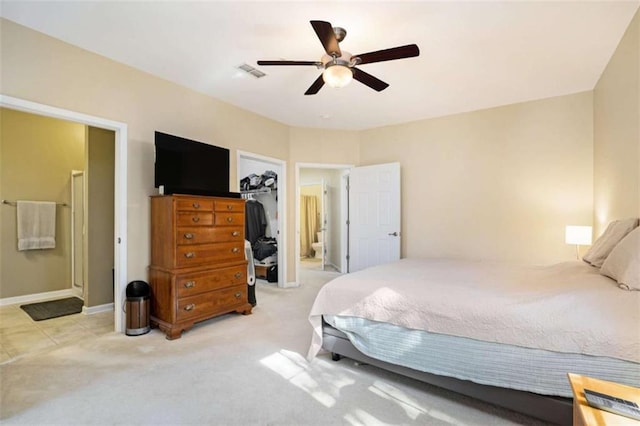 bedroom with light carpet, ceiling fan, a walk in closet, and a closet