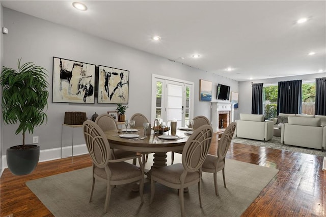 dining area featuring a brick fireplace and hardwood / wood-style flooring