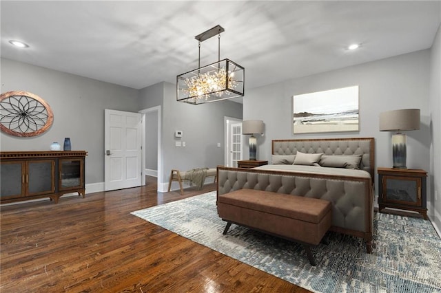 bedroom with dark hardwood / wood-style floors and a chandelier