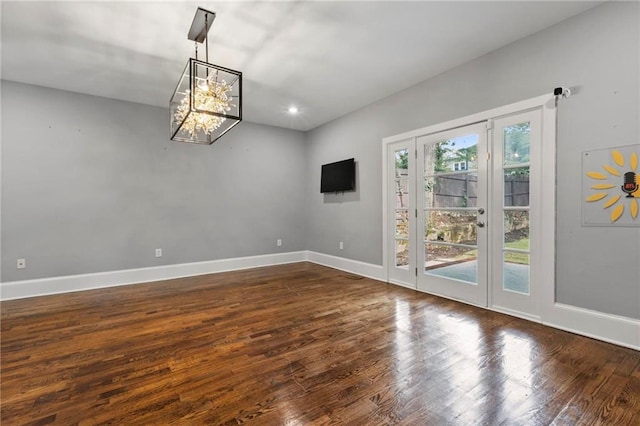 spare room with a notable chandelier and dark hardwood / wood-style floors