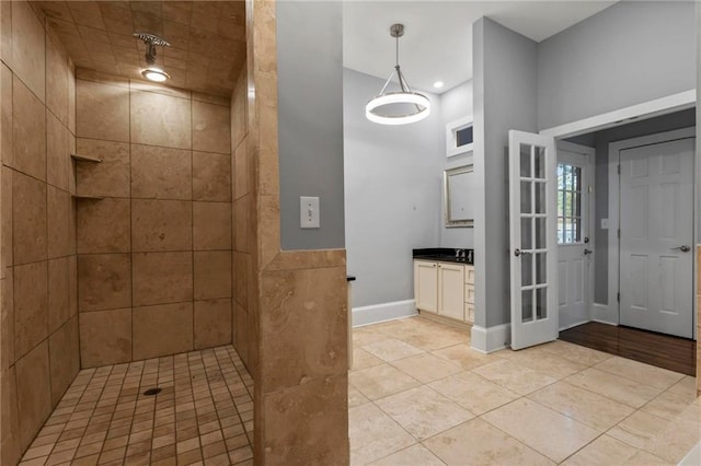 bathroom featuring a tile shower, tile patterned flooring, and vanity