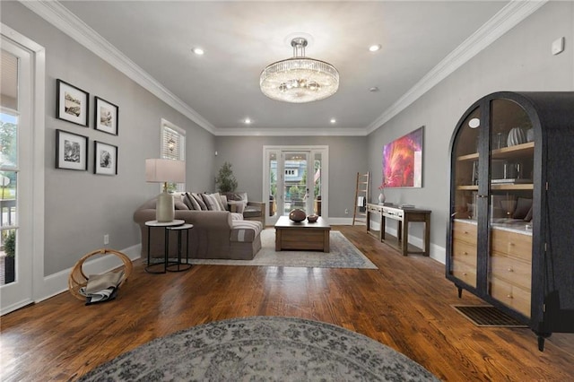 living room with ornamental molding, a notable chandelier, and dark wood-type flooring