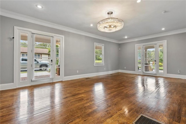 spare room with hardwood / wood-style flooring, ornamental molding, a chandelier, and plenty of natural light