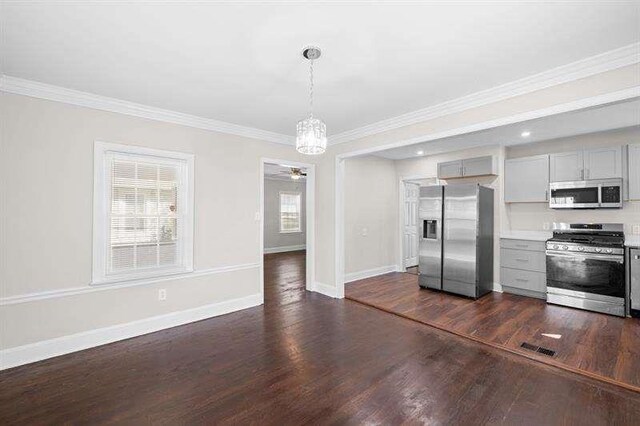 kitchen featuring gray cabinetry, dark wood-type flooring, hanging light fixtures, ornamental molding, and appliances with stainless steel finishes