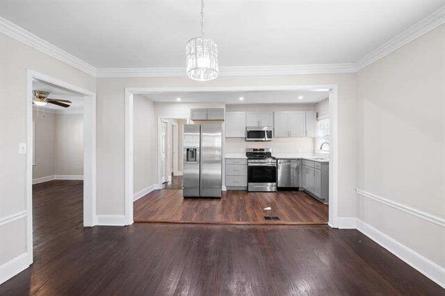 kitchen with sink, decorative light fixtures, appliances with stainless steel finishes, ceiling fan with notable chandelier, and ornamental molding