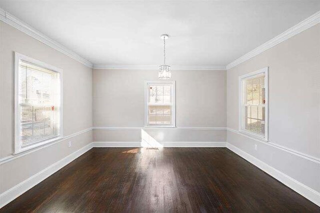 empty room with a chandelier, dark wood-type flooring, and crown molding