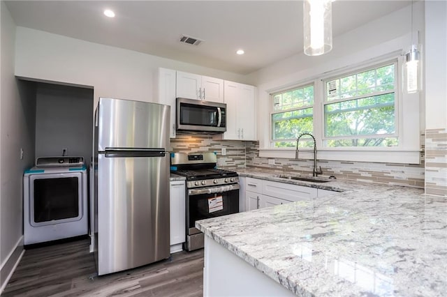 kitchen featuring washer / dryer, white cabinetry, dark wood-type flooring, decorative light fixtures, and stainless steel appliances