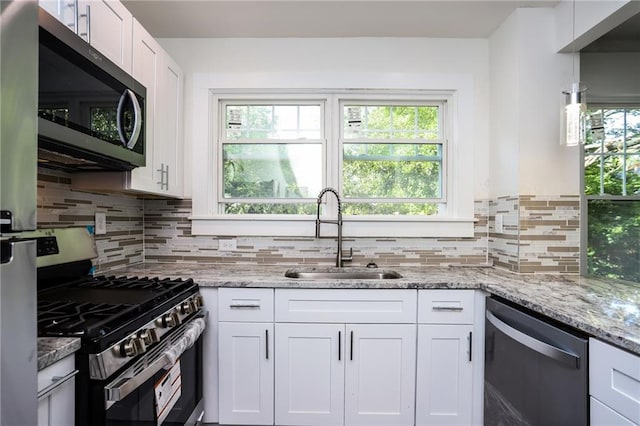 kitchen featuring a wealth of natural light, sink, appliances with stainless steel finishes, and white cabinets