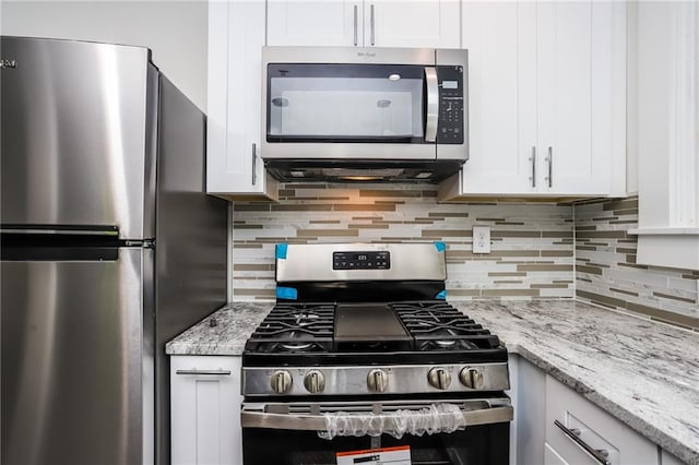 kitchen with white cabinetry, light stone counters, stainless steel appliances, and decorative backsplash