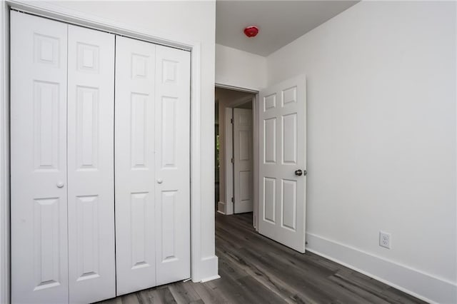 unfurnished bedroom featuring a closet and dark hardwood / wood-style flooring