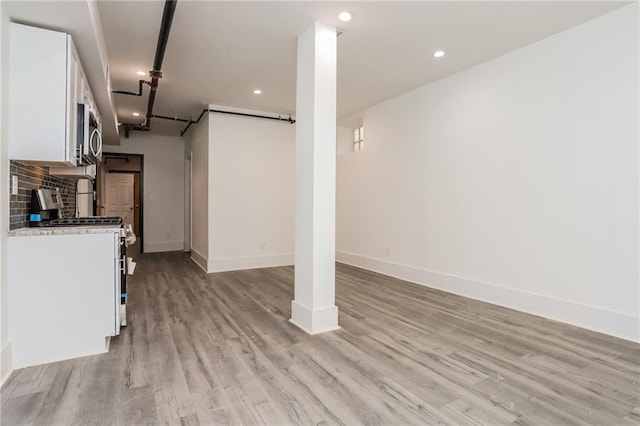 interior space with light hardwood / wood-style floors, white cabinetry, backsplash, and white stove