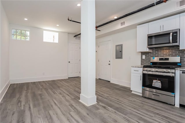 kitchen featuring electric panel, appliances with stainless steel finishes, light wood-type flooring, and white cabinetry