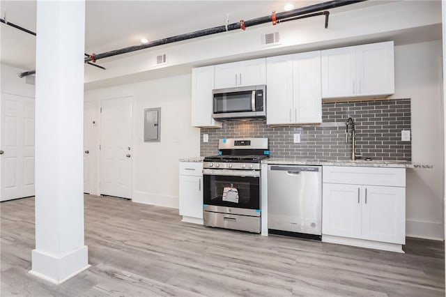 kitchen featuring decorative backsplash, light hardwood / wood-style flooring, white cabinets, and stainless steel appliances