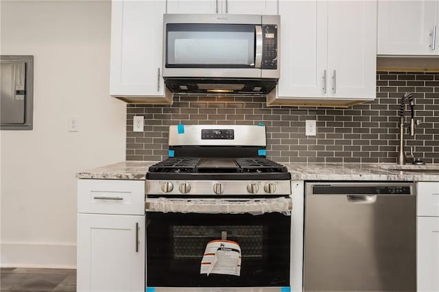 kitchen with white cabinetry, light stone countertops, tasteful backsplash, and appliances with stainless steel finishes