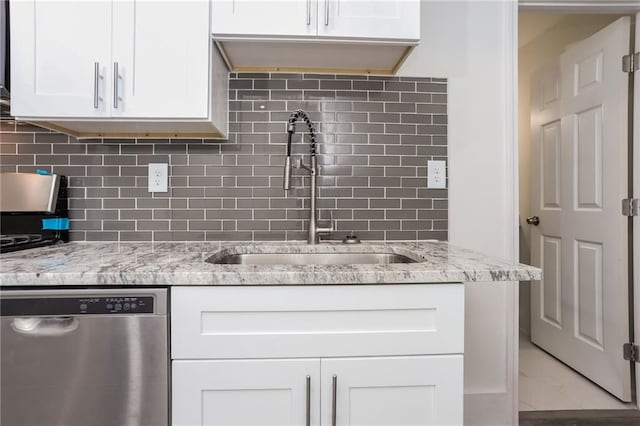 kitchen with dishwasher, backsplash, sink, white cabinets, and light stone counters