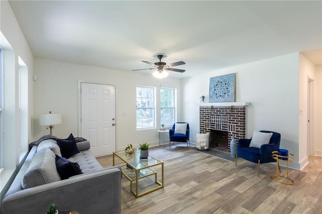 living room with baseboards, a fireplace, wood finished floors, and a ceiling fan