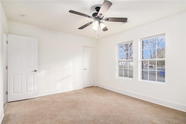 empty room featuring baseboards, light colored carpet, and ceiling fan