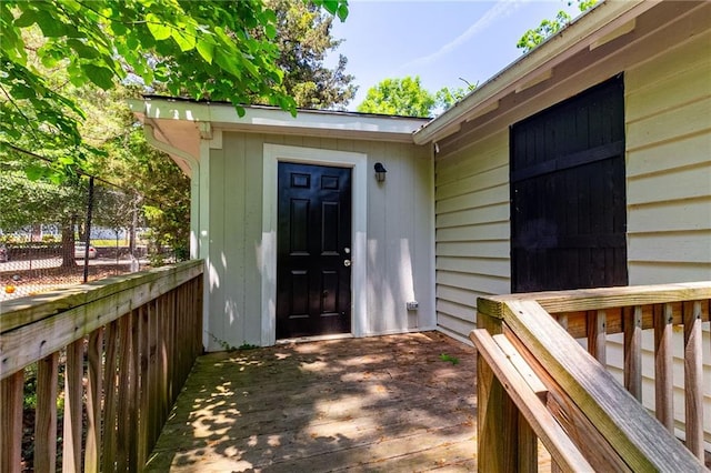 view of exterior entry featuring a deck and fence