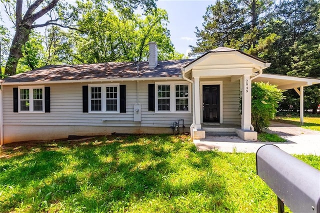 view of front of home featuring a carport, a front yard, and a chimney