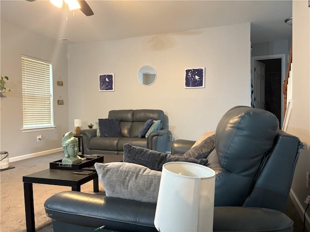 carpeted living room with baseboards and a ceiling fan