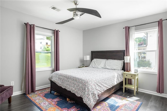 bedroom featuring baseboards, visible vents, multiple windows, and wood finished floors