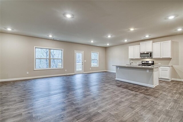 interior space featuring sink, coffered ceiling, light hardwood / wood-style floors, and a center island with sink