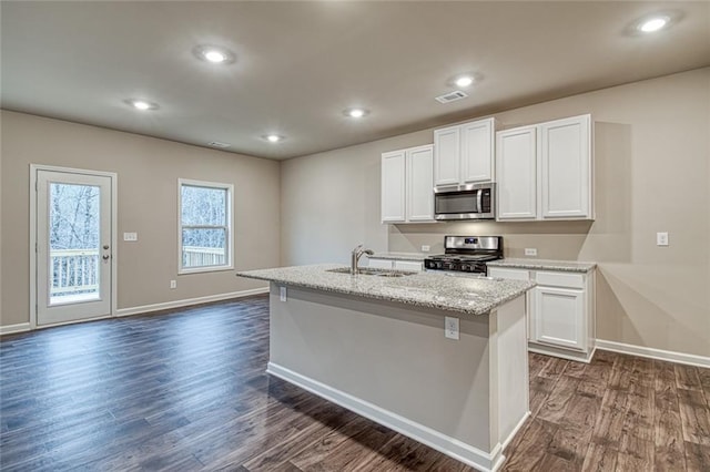 kitchen with sink, white cabinetry, stainless steel appliances, an island with sink, and dark hardwood / wood-style flooring