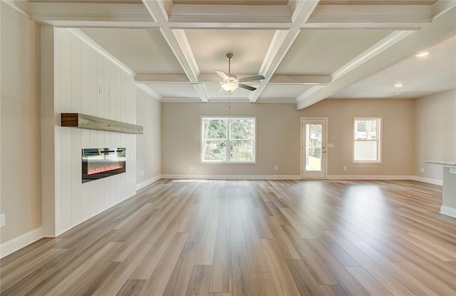 unfurnished living room featuring a fireplace, coffered ceiling, ceiling fan, light hardwood / wood-style floors, and beam ceiling