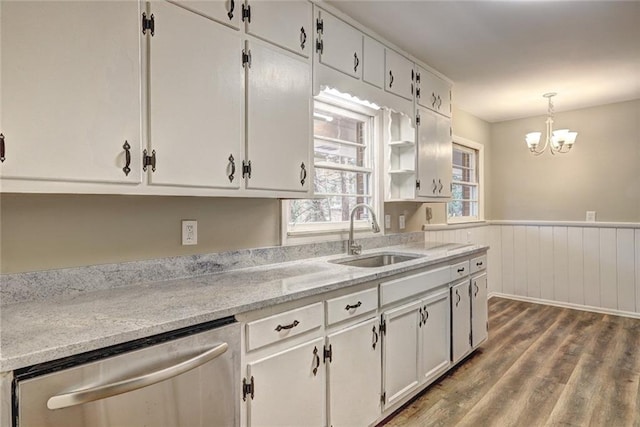 kitchen featuring stainless steel dishwasher, sink, wood-type flooring, decorative light fixtures, and white cabinetry