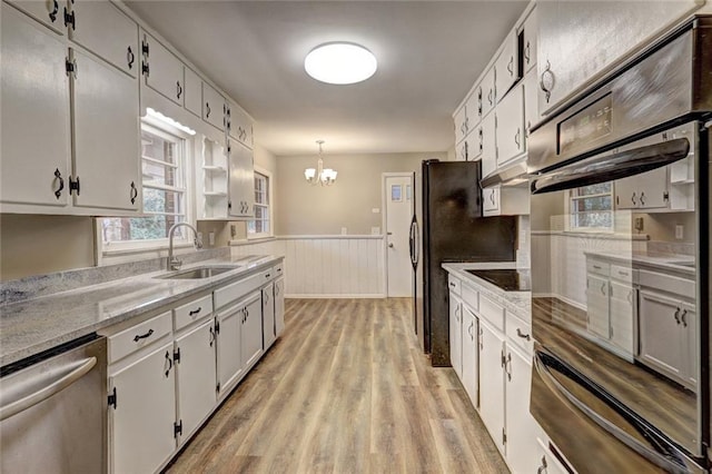 kitchen featuring sink, black appliances, decorative light fixtures, white cabinets, and light hardwood / wood-style floors