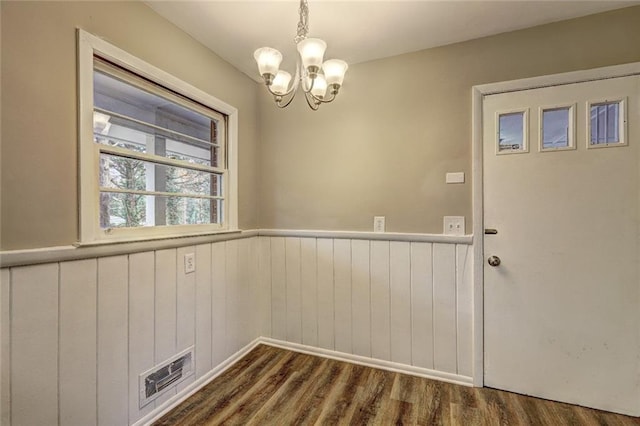 unfurnished dining area with dark wood-type flooring and a notable chandelier