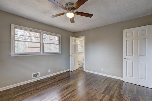 unfurnished bedroom featuring a textured ceiling, ceiling fan, dark wood-type flooring, and connected bathroom