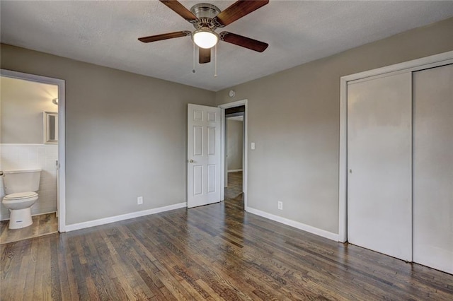 unfurnished bedroom with a closet, dark hardwood / wood-style flooring, ensuite bathroom, and ceiling fan