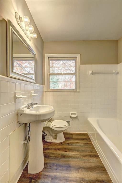 bathroom featuring hardwood / wood-style flooring, a washtub, and tile walls