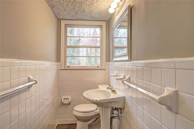 bathroom with hardwood / wood-style floors, a textured ceiling, toilet, and tile walls