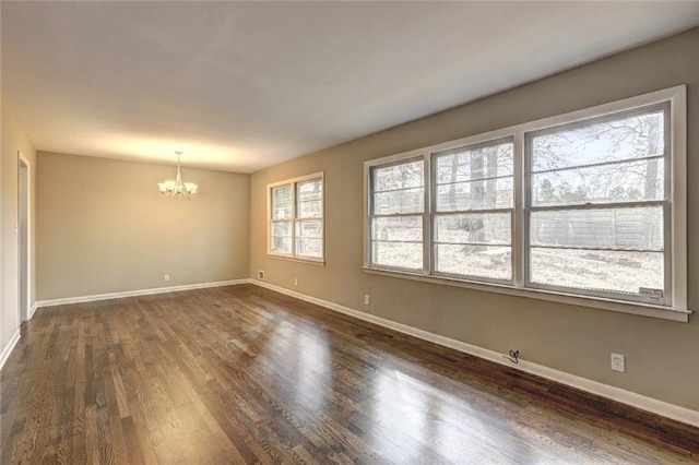 empty room with dark hardwood / wood-style flooring and an inviting chandelier