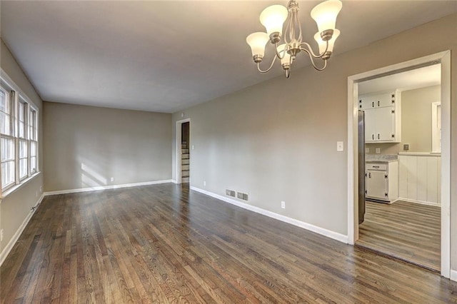 empty room featuring a chandelier and dark hardwood / wood-style floors