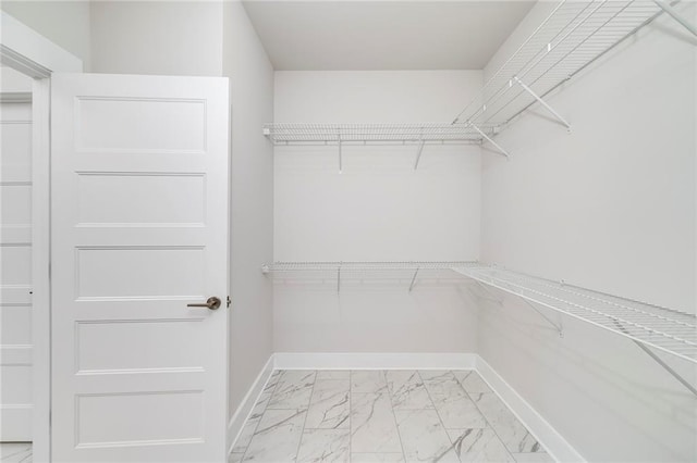 walk in closet featuring marble finish floor