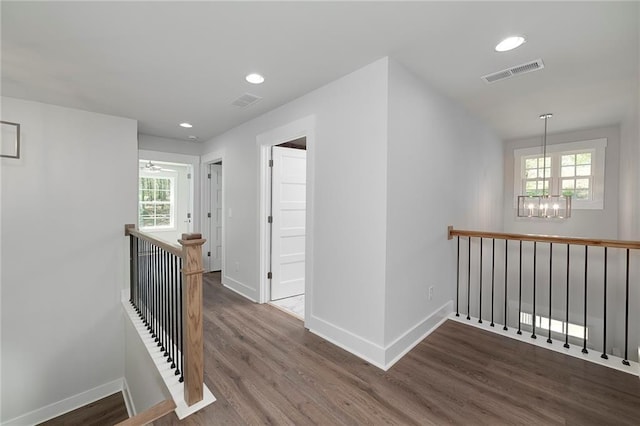 hall featuring a wealth of natural light, visible vents, wood finished floors, an upstairs landing, and a notable chandelier