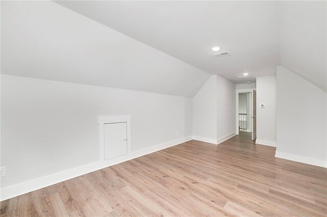 bonus room featuring visible vents, baseboards, light wood-style flooring, and lofted ceiling
