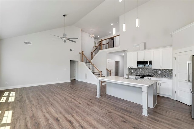 kitchen featuring stainless steel microwave, a ceiling fan, visible vents, high vaulted ceiling, and stove