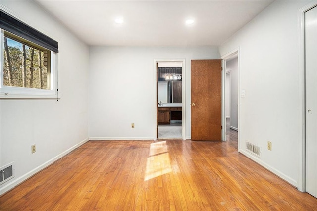 unfurnished bedroom featuring a sink, baseboards, visible vents, and light wood-type flooring