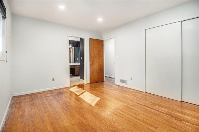 unfurnished bedroom featuring visible vents, baseboards, recessed lighting, light wood-style floors, and ensuite bath